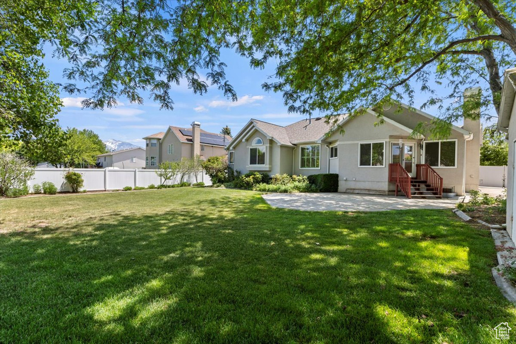 Rear view of property featuring a patio area, a chimney, entry steps, and stucco siding