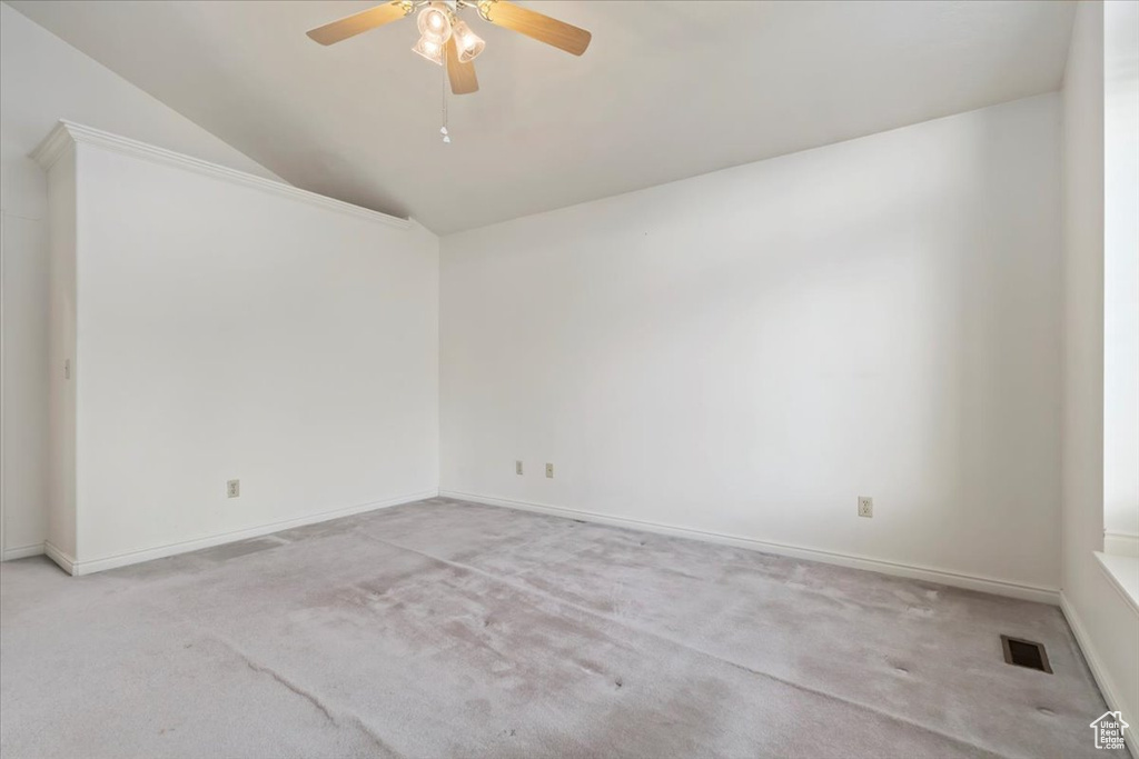 Carpeted spare room featuring lofted ceiling, ceiling fan, and baseboards