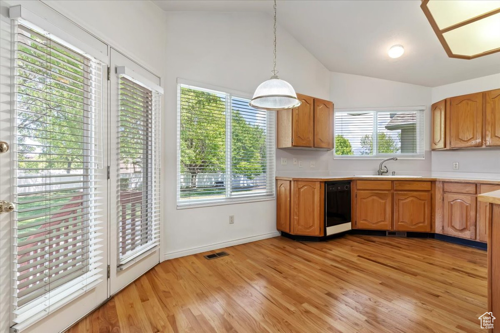Kitchen with black dishwasher, light countertops, a sink, vaulted ceiling, and healthy amount of natural light