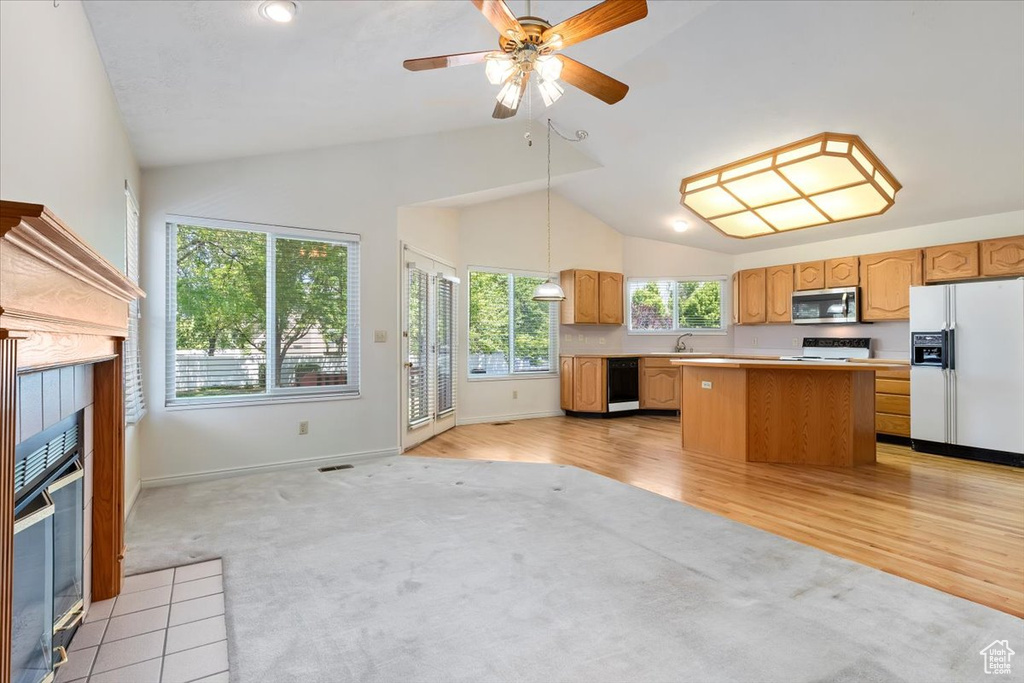Kitchen with white appliances, light carpet, high vaulted ceiling, a center island, and light countertops