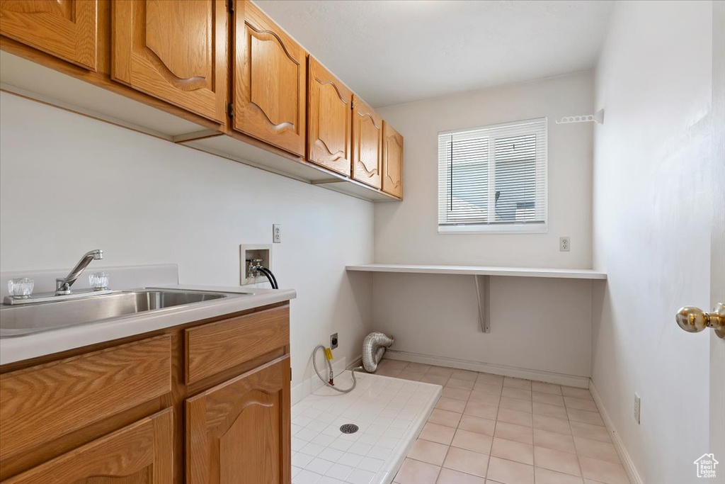 Laundry room featuring hookup for an electric dryer, washer hookup, cabinet space, light tile patterned flooring, and baseboards