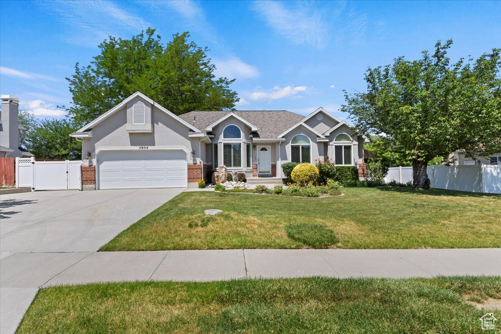 Ranch-style home with concrete driveway, a garage, a gate, and stucco siding