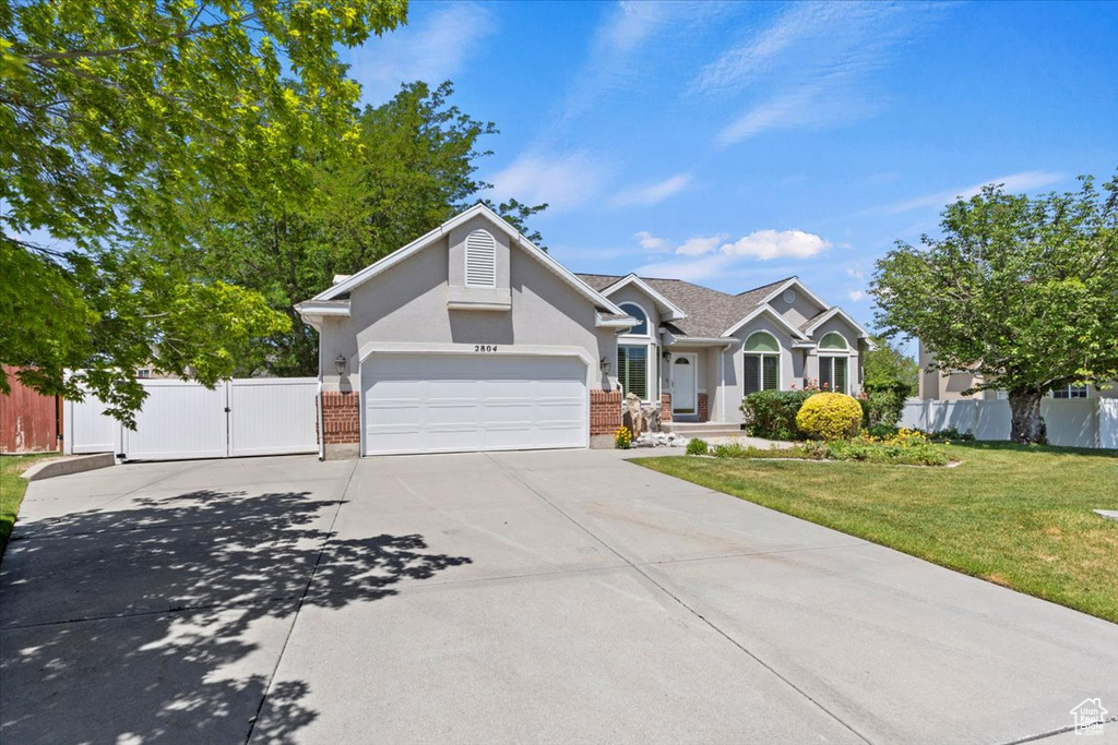 View of front facade with concrete driveway, a gate, a garage, and brick siding
