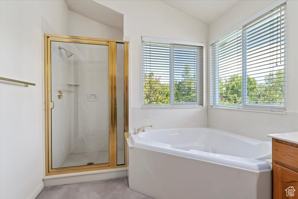 Bathroom featuring healthy amount of natural light, a shower stall, vaulted ceiling, and a garden tub