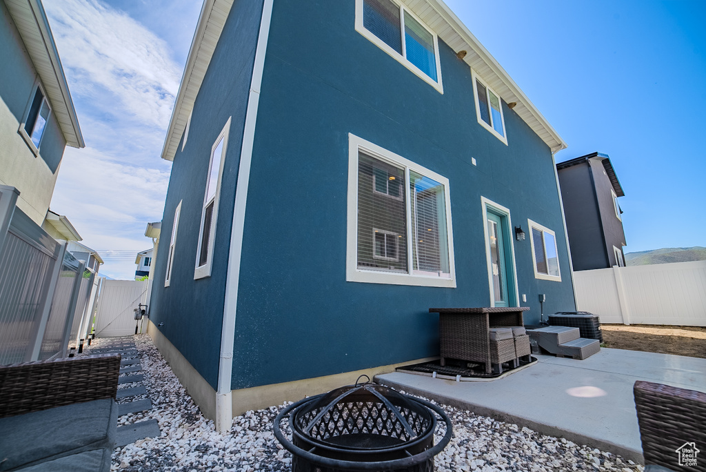 View of property exterior featuring a fenced backyard, a gate, a patio area, an outdoor fire pit, and stucco siding