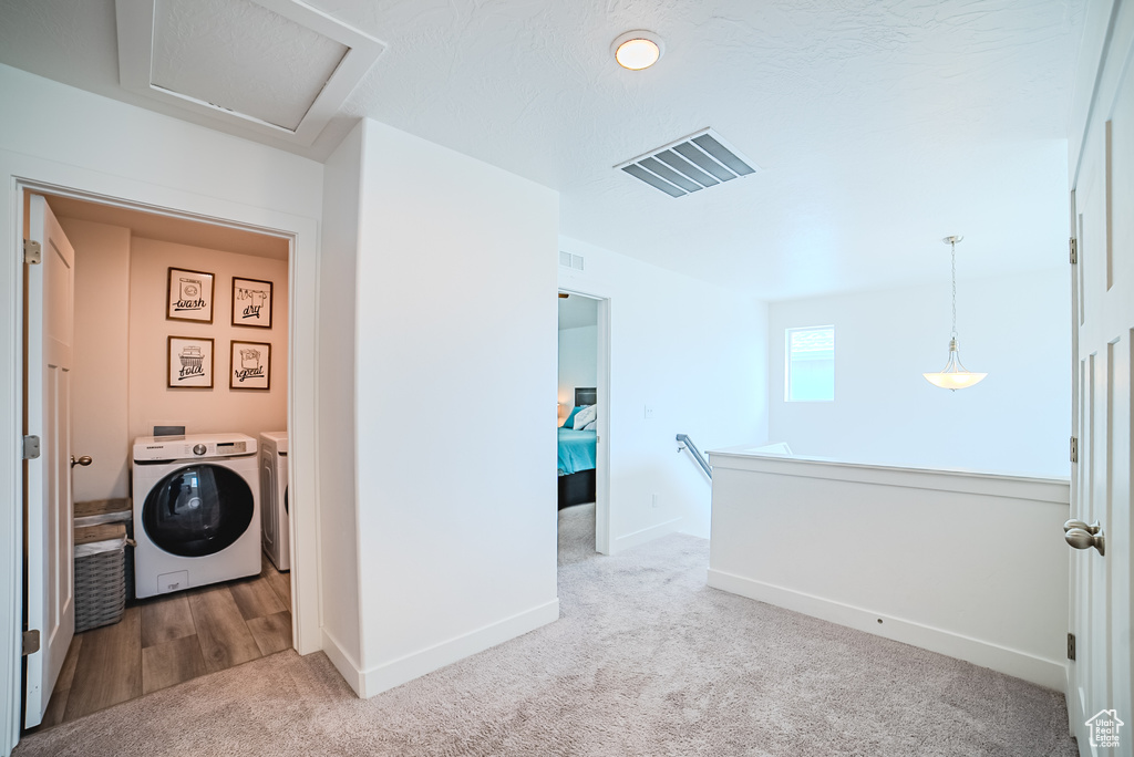 Laundry room with washer and dryer, light colored carpet, baseboards, and attic access