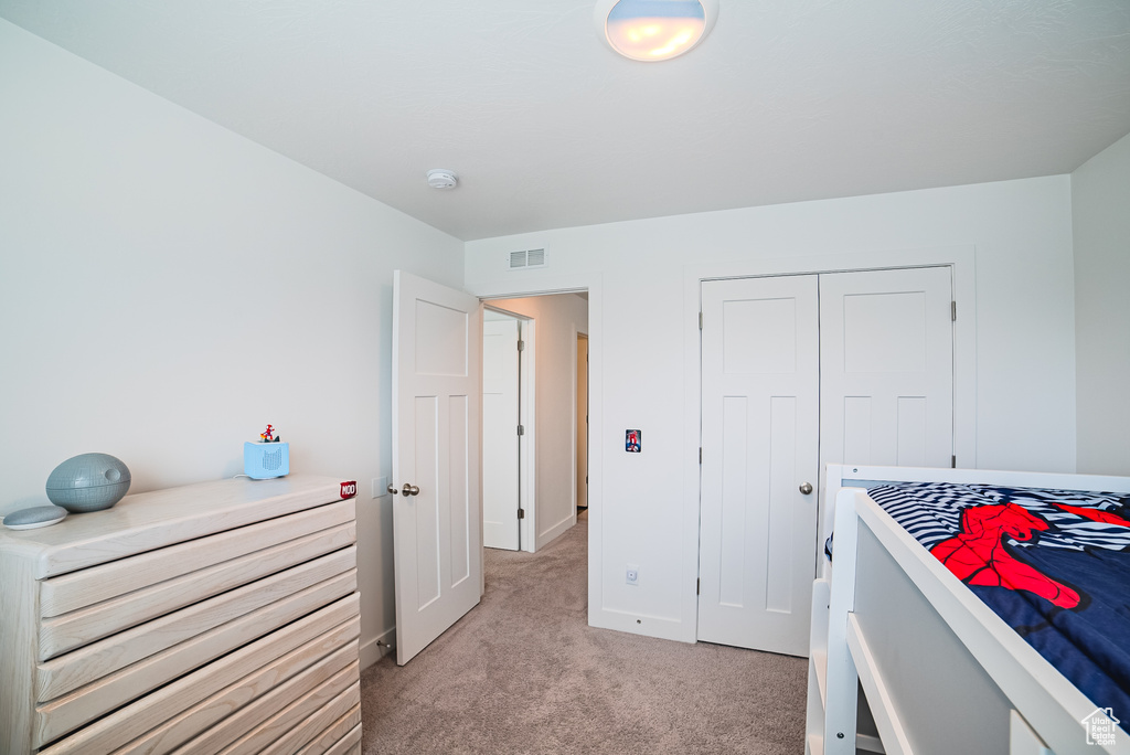 Bedroom featuring light carpet, a closet, and baseboards