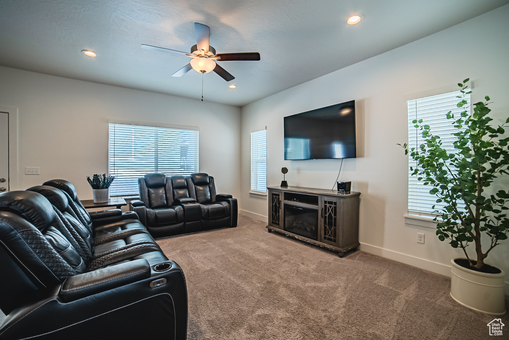 Living area with a ceiling fan, carpet, baseboards, a fireplace, and recessed lighting