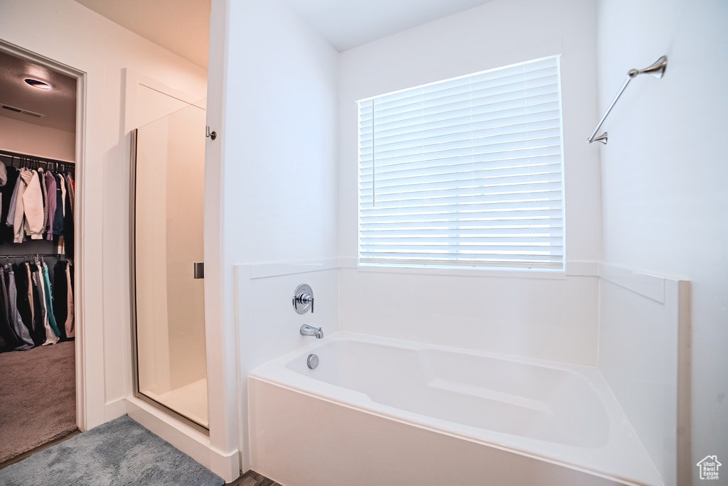 Full bath featuring a garden tub, a spacious closet, and a stall shower