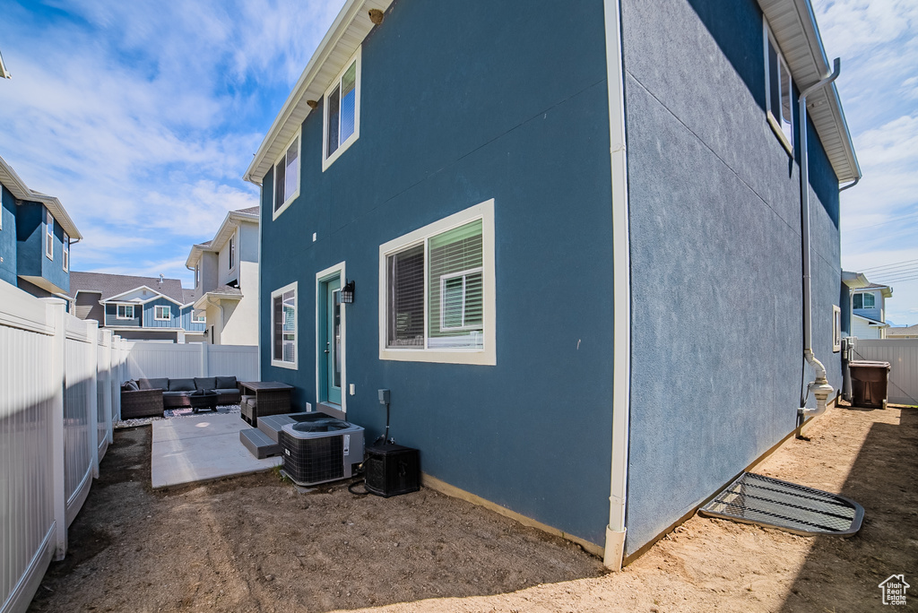 View of property exterior featuring an outdoor living space, a patio, a fenced backyard, central AC unit, and stucco siding