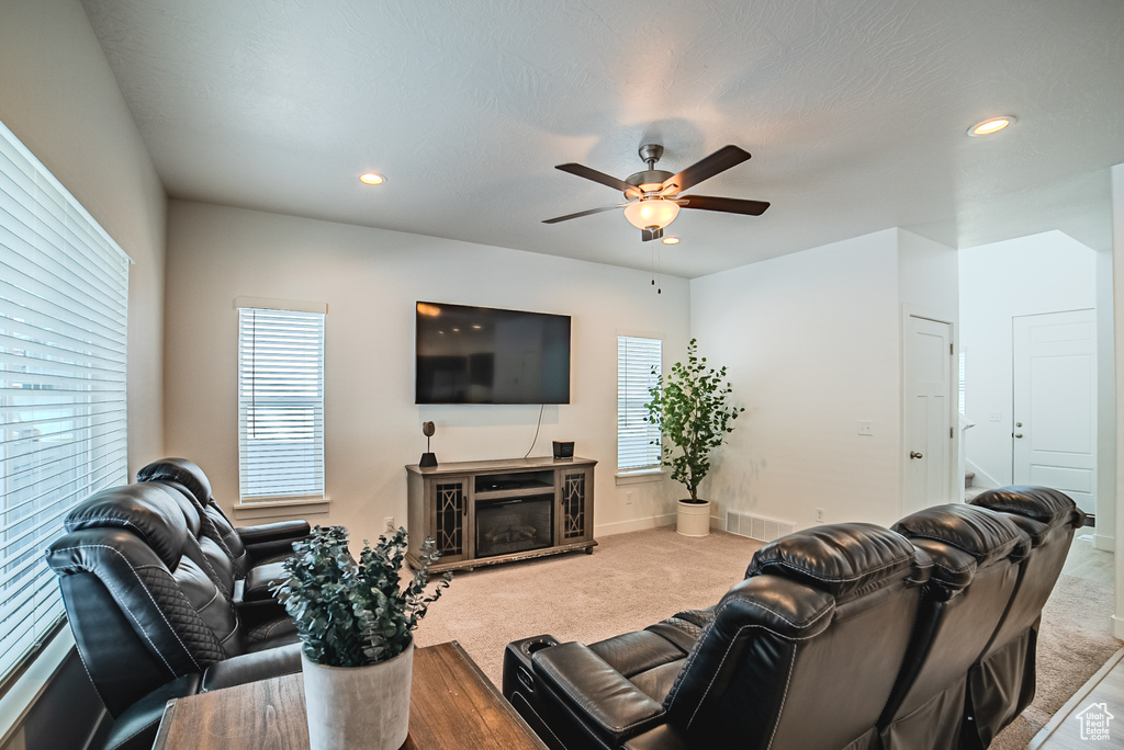 Living room with ceiling fan, recessed lighting, carpet, baseboards, and a glass covered fireplace