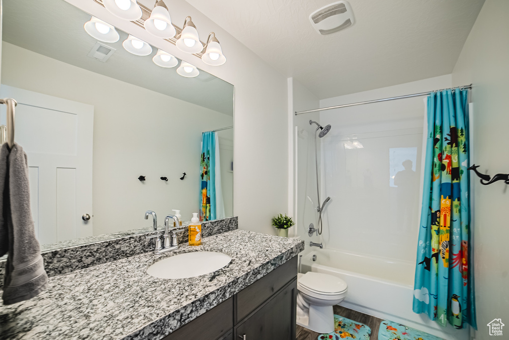 Full bathroom with vanity, shower / bath combo with shower curtain, wood finished floors, and toilet