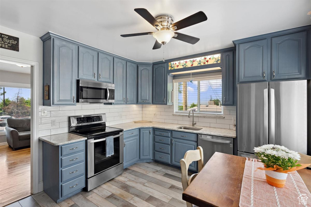 Kitchen with stainless steel appliances, blue cabinetry, plenty of natural light, and a sink