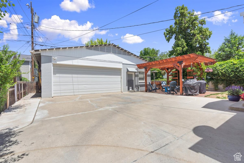 Single story home with a detached garage, a pergola, an outdoor structure, and brick siding