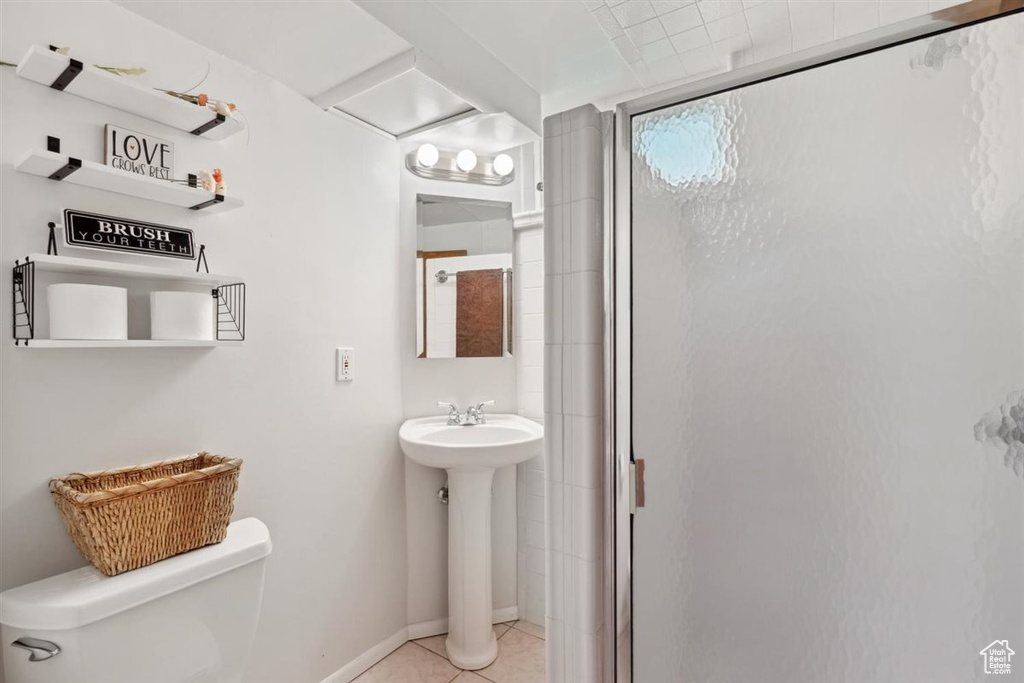 Full bath featuring toilet, a stall shower, a sink, and tile patterned flooring