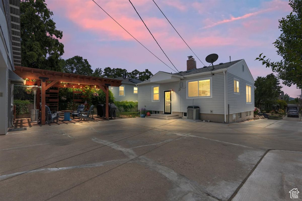 Rear view of house with a chimney, a pergola, a patio, entry steps, and central AC unit
