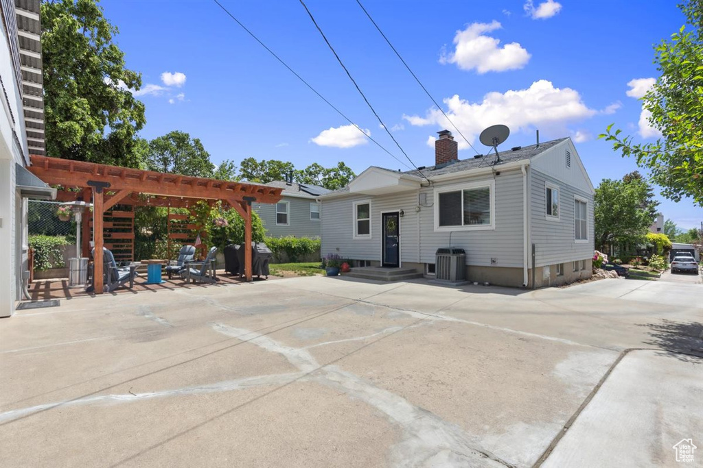 Back of property with a chimney, a pergola, a patio, and central AC unit