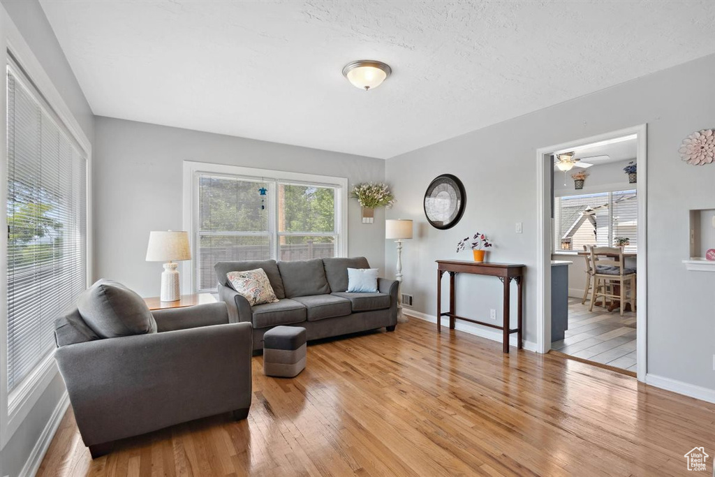 Living area featuring light wood-style floors, baseboards, and ceiling fan