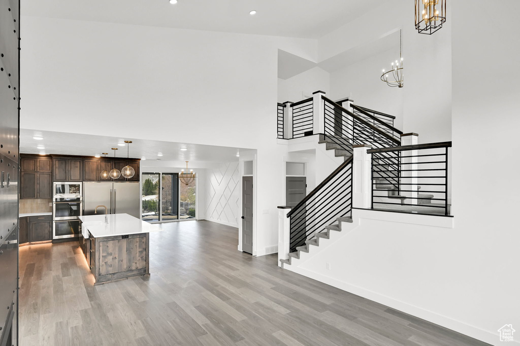 Kitchen featuring light countertops, dark brown cabinetry, light wood-style flooring, a chandelier, and baseboards