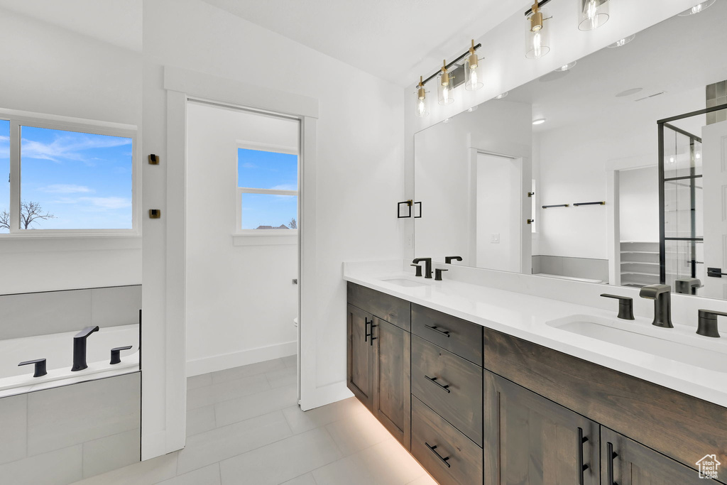 Full bathroom featuring double vanity, tile patterned floors, baseboards, and a shower with door