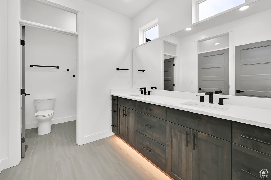 Full bathroom featuring double vanity, toilet, baseboards, and recessed lighting