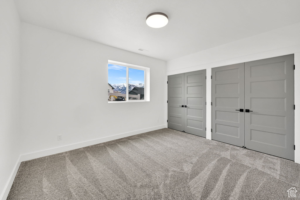Unfurnished bedroom with carpet flooring, two closets, and baseboards