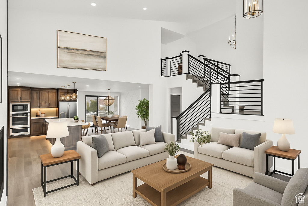 Living area featuring a chandelier, stairway, light wood-style floors, a high ceiling, and recessed lighting