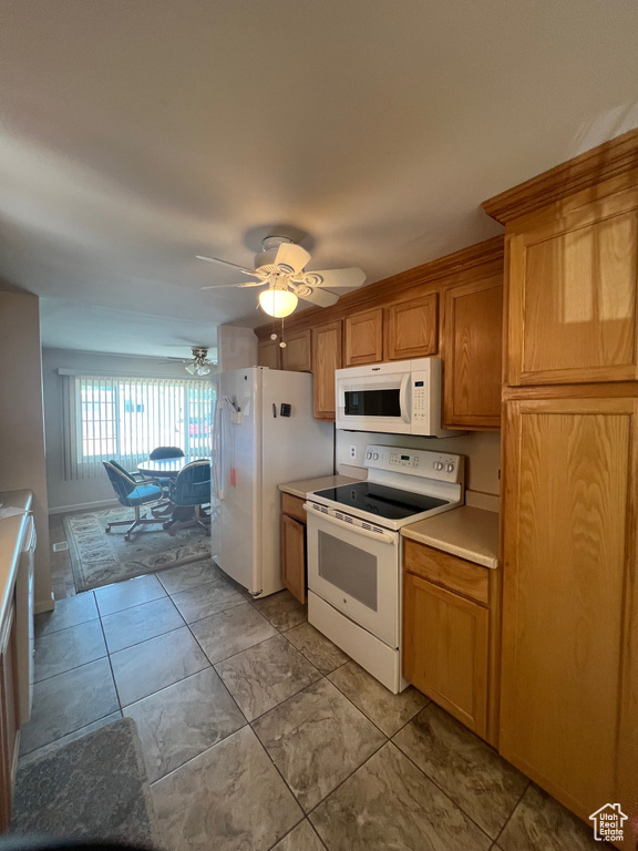 Kitchen featuring white appliances, light countertops, ceiling fan, and brown cabinetry