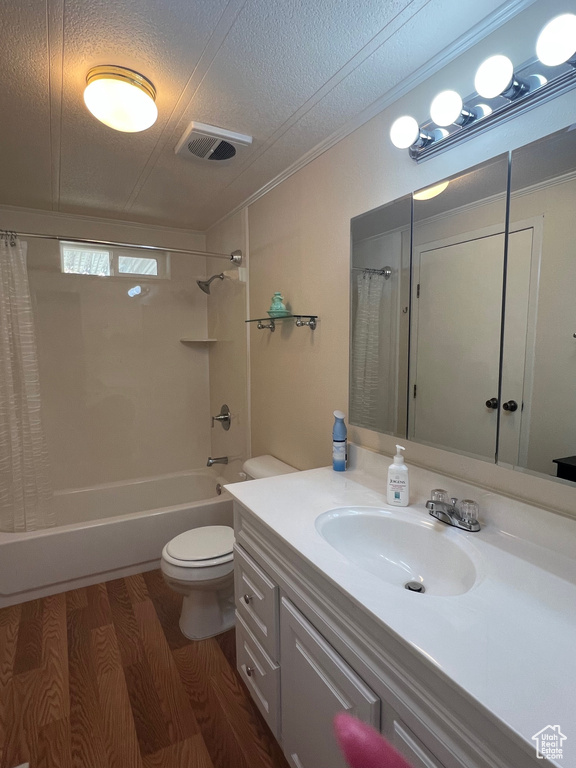 Full bathroom featuring vanity, toilet, a textured ceiling, shower / bathtub combination with curtain, and wood finished floors