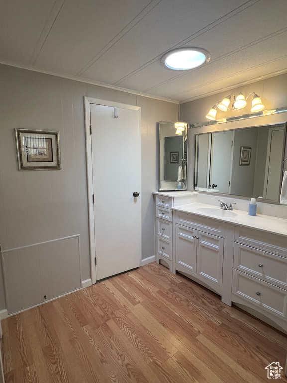 Bathroom with vanity, wood finished floors, crown molding, and baseboards