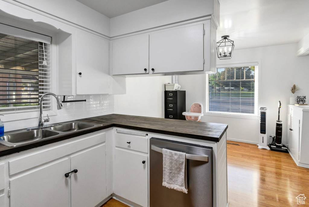Kitchen featuring a sink, dark countertops, stainless steel dishwasher, light wood finished floors, and backsplash
