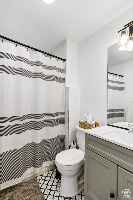 Bathroom featuring vanity, toilet, tile patterned floors, and a shower with curtain