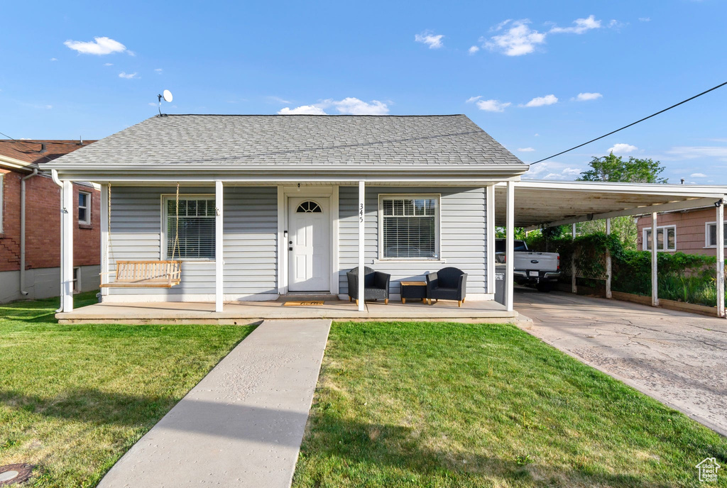 View of front of house featuring a porch, a shingled roof, driveway, and a front yard