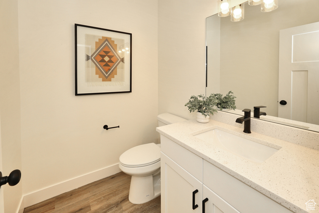 Bathroom featuring vanity, toilet, wood finished floors, and baseboards