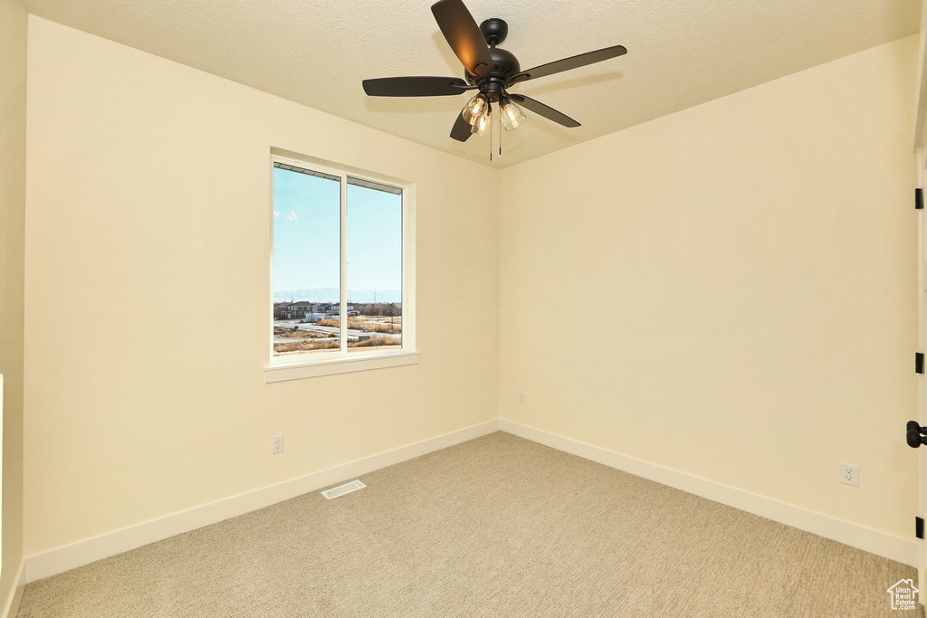 Spare room with light carpet, baseboards, and a ceiling fan
