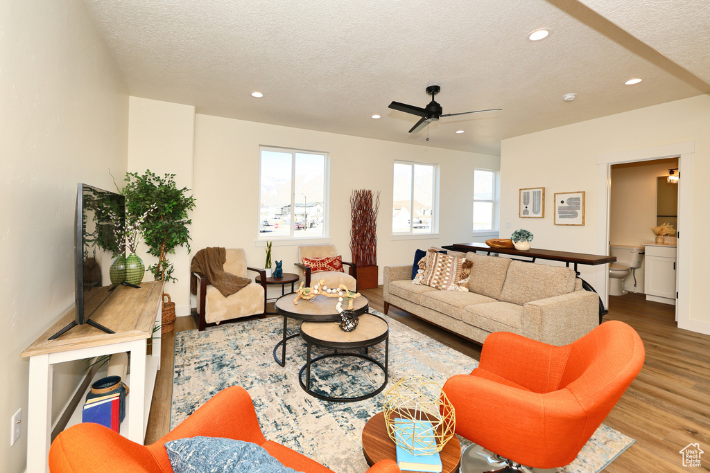 Living area with wood finished floors, a textured ceiling, recessed lighting, a ceiling fan, and baseboards