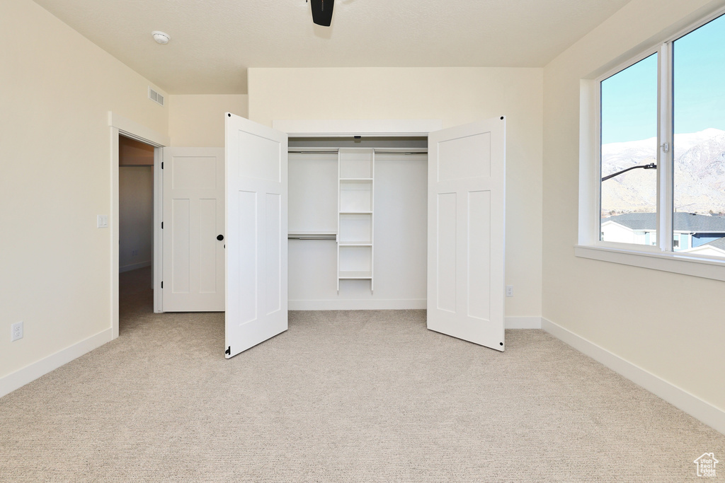 Unfurnished bedroom featuring multiple windows, carpet floors, a closet, and baseboards