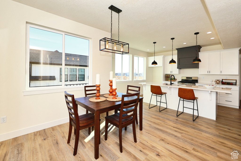 Dining room featuring recessed lighting, light wood-style floors, a textured ceiling, and baseboards