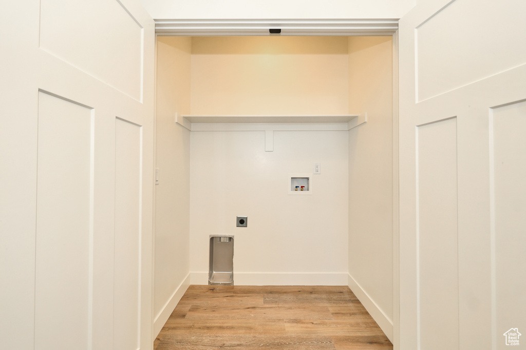 Laundry room with hookup for a washing machine, electric dryer hookup, light wood-style flooring, and baseboards