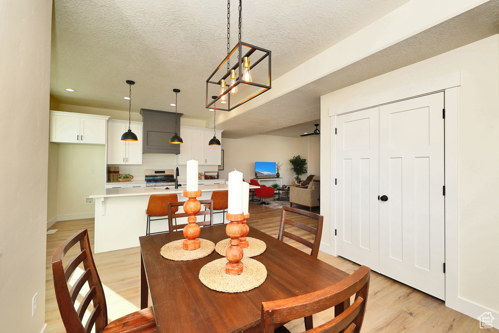 Dining room featuring light wood-style floors, recessed lighting, baseboards, a textured ceiling, and a chandelier