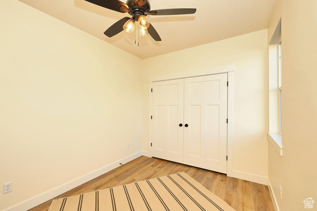 Unfurnished bedroom with baseboards, light wood-type flooring, a closet, and a ceiling fan