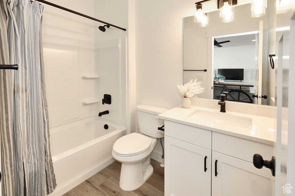 Full bathroom featuring shower / bath combo with shower curtain, vanity, toilet, and wood finished floors