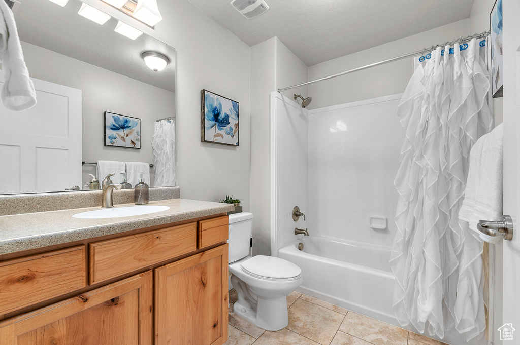 Bathroom featuring tile patterned flooring, vanity, shower / tub combo, and toilet