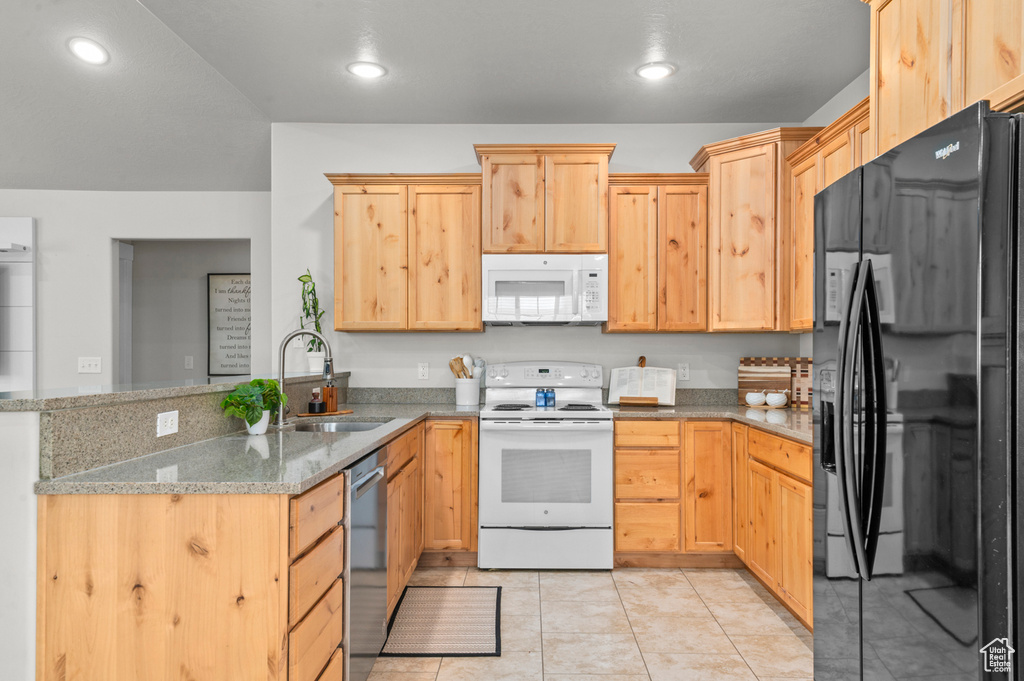 Kitchen featuring white appliances, a sink, a peninsula, light brown cabinets, and light stone counters