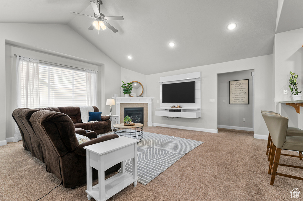 Living room featuring carpet flooring, lofted ceiling, a fireplace, a ceiling fan, and baseboards