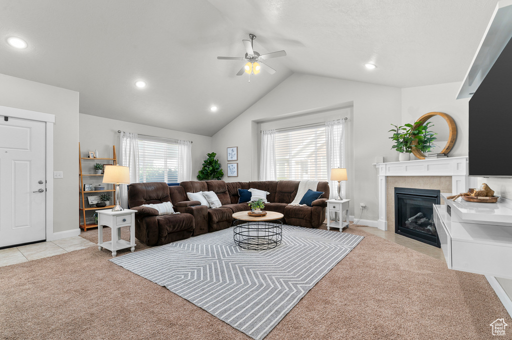 Living room with a tiled fireplace, ceiling fan, light carpet, vaulted ceiling, and recessed lighting