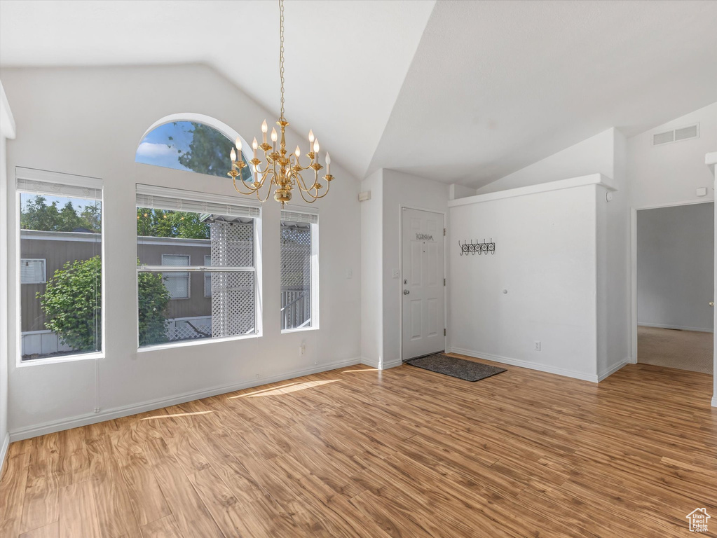 Entryway featuring vaulted ceiling, wood finished floors, a chandelier, and baseboards
