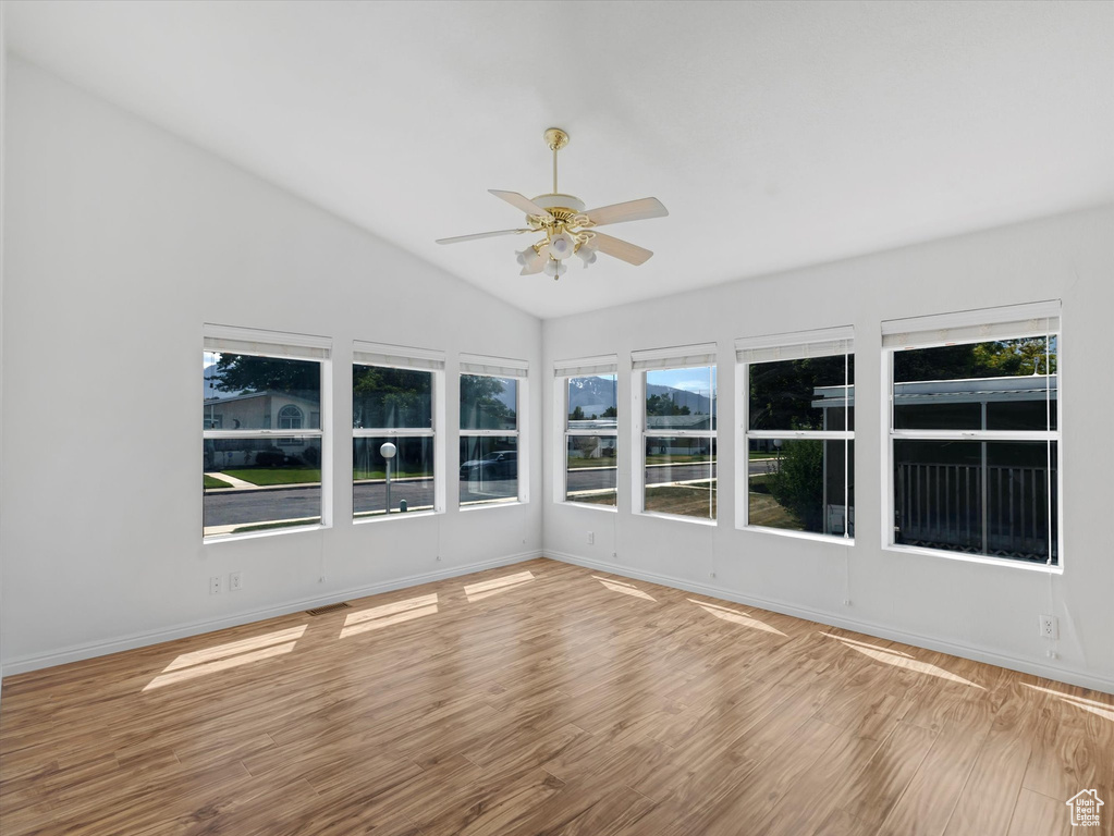 Unfurnished sunroom with wood finished floors, lofted ceiling, baseboards, and a deck