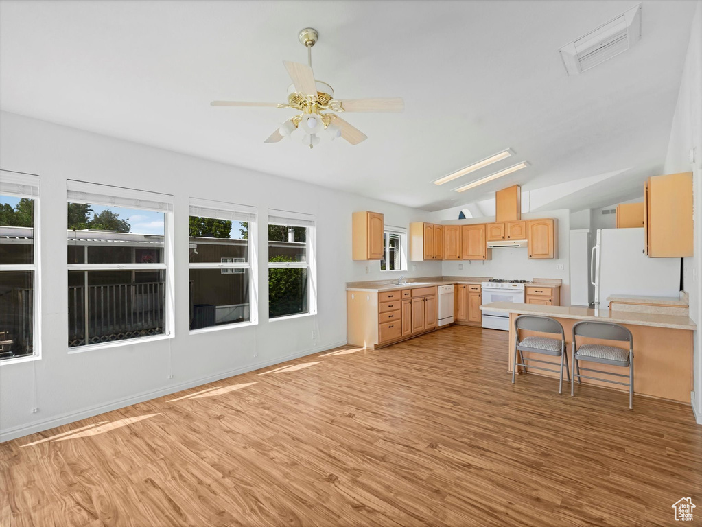Kitchen featuring white appliances, light brown cabinetry, light wood-type flooring, lofted ceiling, and light countertops