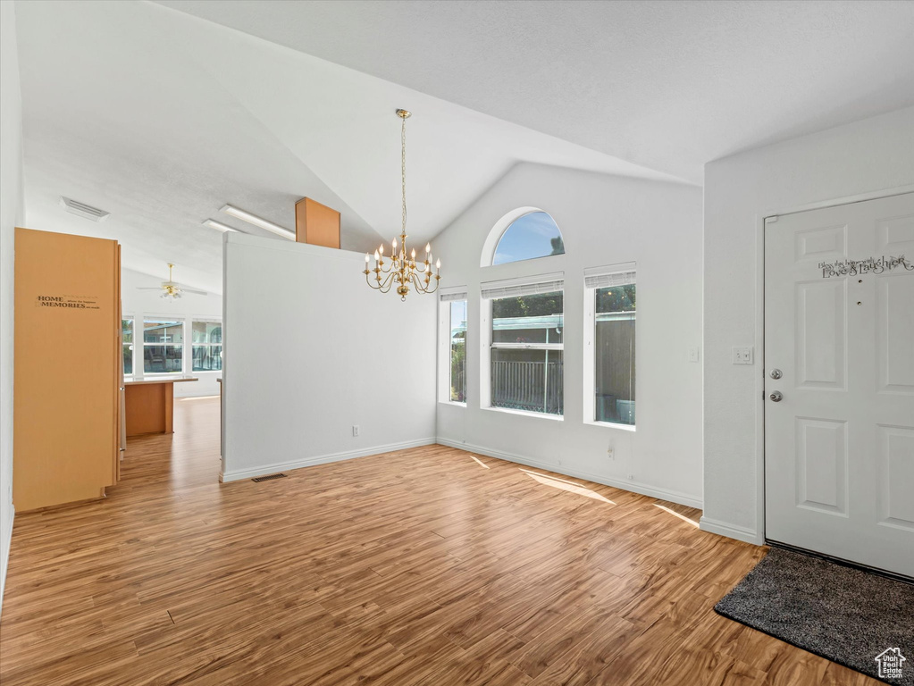 Foyer entrance with a chandelier, wood finished floors, lofted ceiling, baseboards, and a ceiling fan